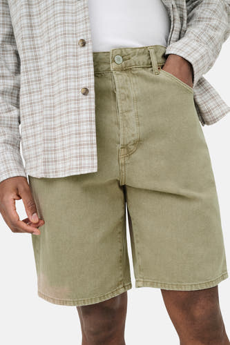 Beige jeansshort van ONLY & SONS met metalen knoop en lichte textuur, gedragen met geruit overhemd en wit T-shirt.