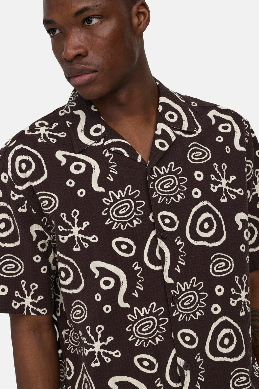 Bruin overhemd met korte mouwen van ONLY & SONS® met reliëfstructuur en witte abstracte print, gedragen door een man.