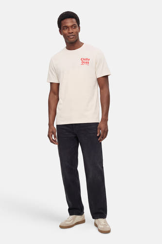 Ecru T-shirt met korte mouwen van ONLY & SONS®, met een rode tekstprint en gecombineerd met een donkere jeans en sneakers.

