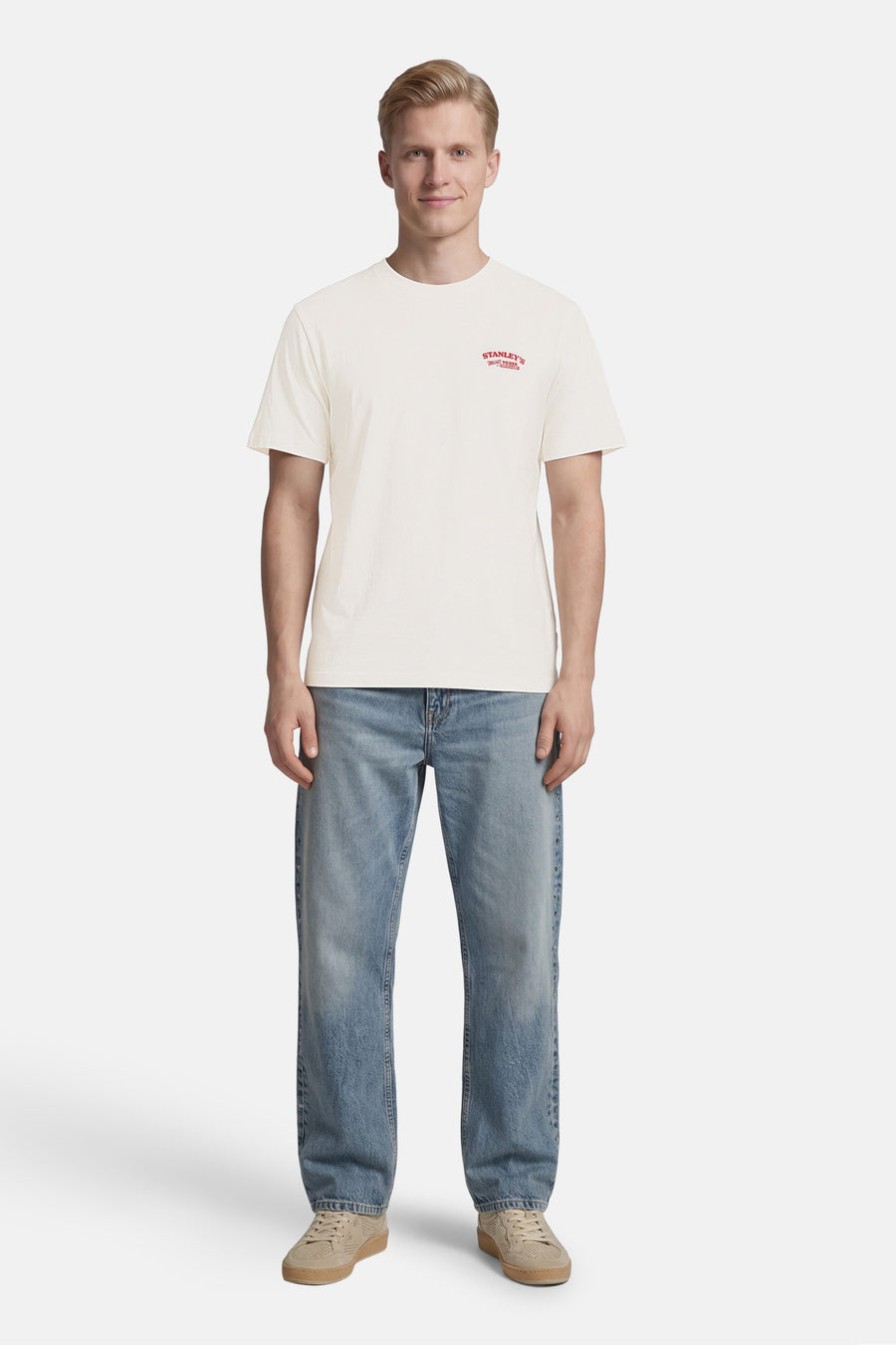 T-shirt de couleur crème de ONLY & SONS® avec petit imprimé rouge sur la poitrine, porté avec un jean bleu et des baskets beiges.
