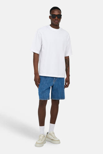 Mid-blauwe denim short van ONLY & SONS, gedragen door een man met een wit T-shirt en beige sneakers.