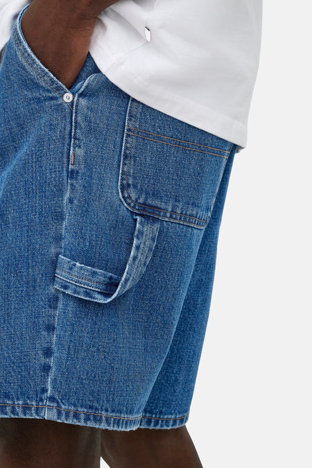 Mid-blauwe denim short van ONLY & SONS® met carpenterzak en tool loop, gedragen met een wit T-shirt.