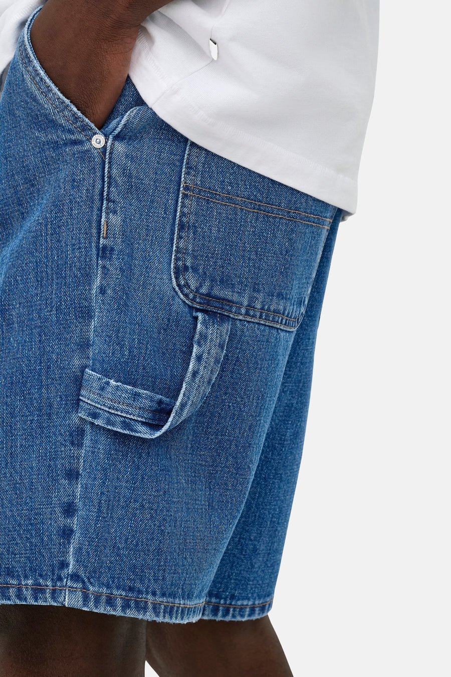 Short en jean bleu moyen de ONLY & SONS® avec poche carpenter et passant à outils, porté avec un t-shirt blanc.