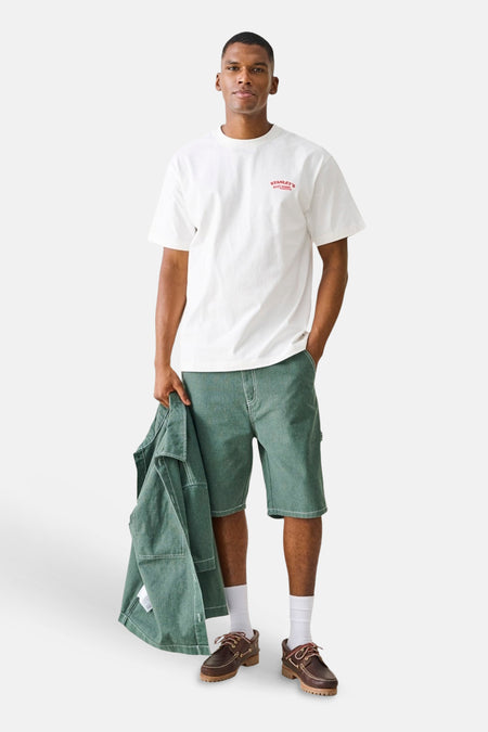 Groene short van ONLY & SONS® met witte stiksels, gedragen door een man in wit T-shirt en bruine loafers.