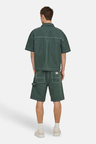 Groene shorts van ONLY & SONS® met wit contraststiksel en utility zakken, gedragen met een bijpassend overhemd.
