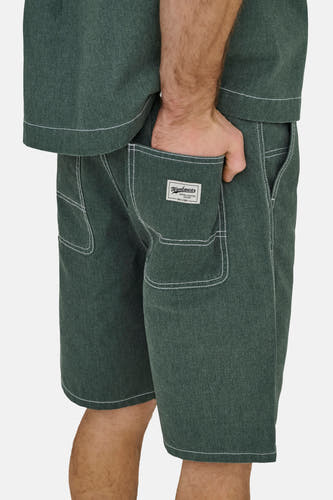 Groene shorts van ONLY & SONS® met witte contraststiksels, een textuur en label op de achterzak, gedragen met hand in zak.
