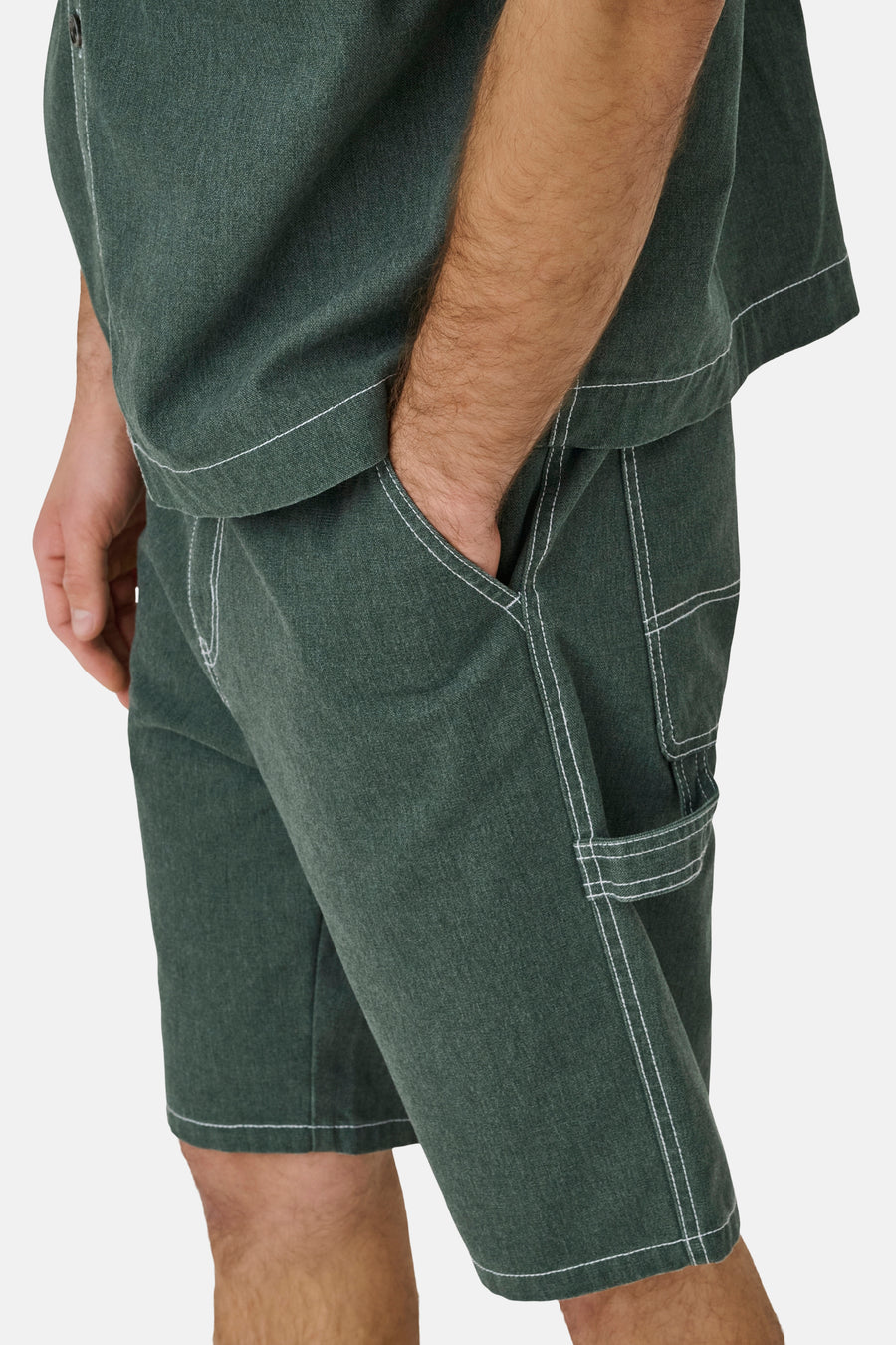 Groene short van ONLY & SONS® met contrasterende witte stiksels, een hand in de zak en gereedschapslus.