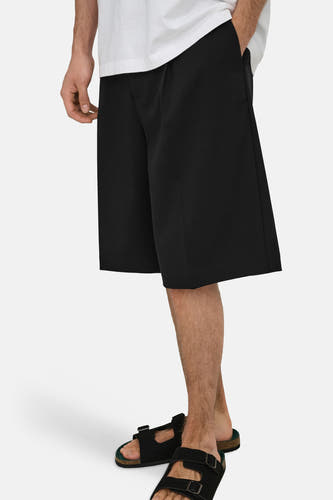 Zwarte korte broek van ONLY & SONS® met rechte pasvorm, gedragen met wit overhemd en zwarte sandalen, zijprofiel.
