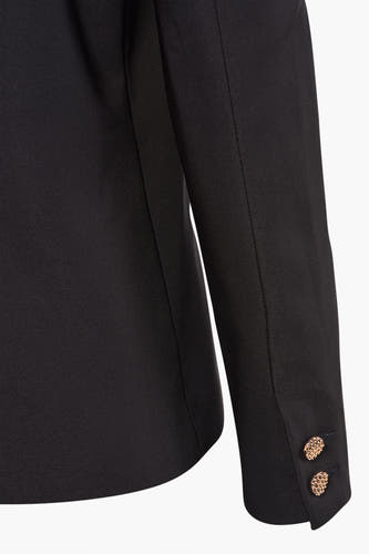 Blazer noir de Morgan De Toi, avec des boutons décoratifs dorés sur la manche, en gros plan.