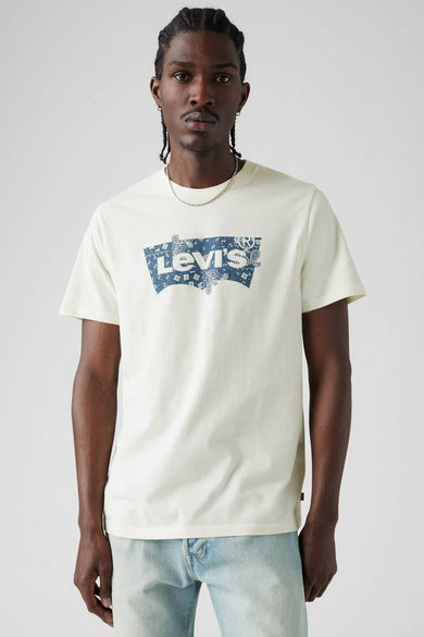 Beige T-shirt met korte mouwen van Levi's® met blauw logo op de borst en gedragen met een zilveren ketting.
