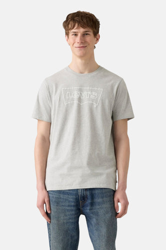 Een man met een grijs T-shirt met een Levi's logo en blauwe jeans.