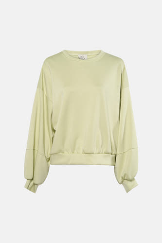 Pull vert Terra di Siena, à manches longues et associé à un jean ample et des escarpins noirs.