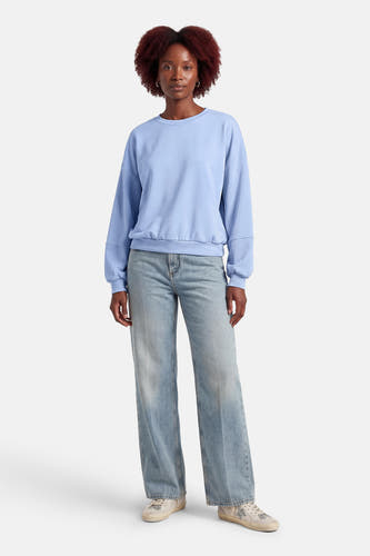 Blauwe sweater van Terra di Siena, met lange mouwen en gecombineerd met jeans en sneakers.