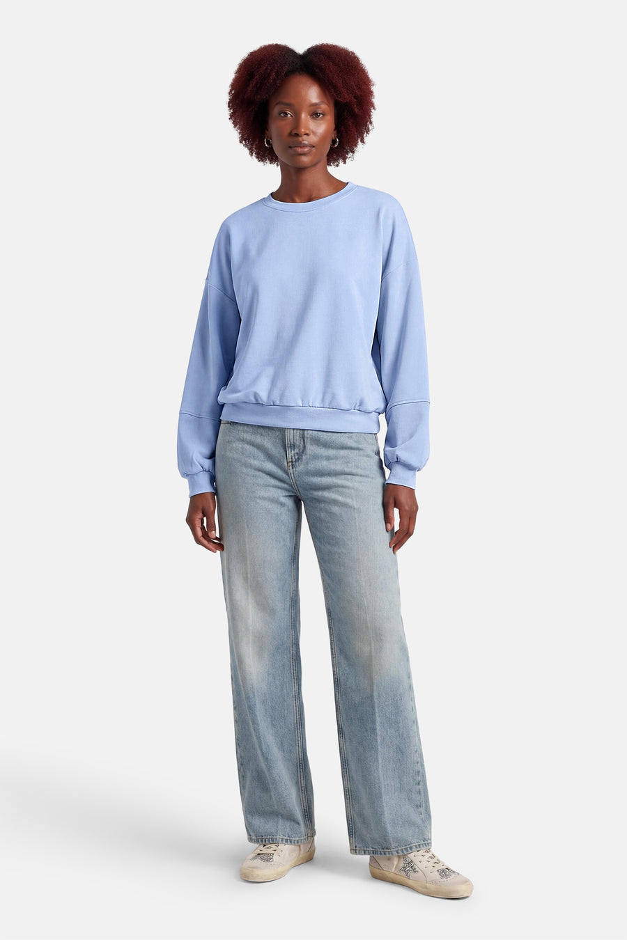 Blauwe sweater van Terra di Siena, met lange mouwen en gecombineerd met jeans en sneakers.