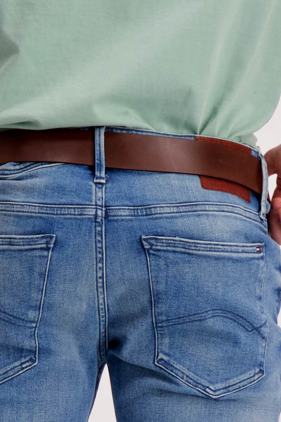 Ceinture brune de Levi's® Accessories, portée avec un jean bleu et une chemise vert clair, vue de derrière.