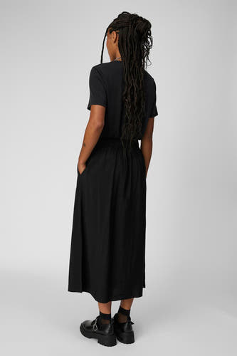 T-shirt noir d'OBJECT, avec des longs tresses, une longue jupe et de grosses chaussures noires.