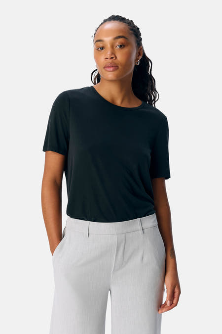 Zwart T-shirt van OBJECT, gedragen met een grijze pantalon en zilverkleurige oorbellen.
