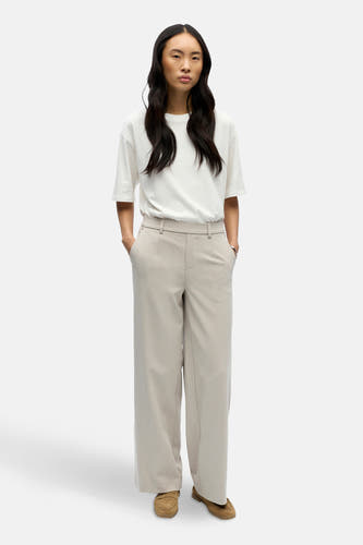 Ecru broek van OBJECT, met wijde pijpen en steekzakken, gecombineerd met een wit T-shirt en bruine schoenen.
