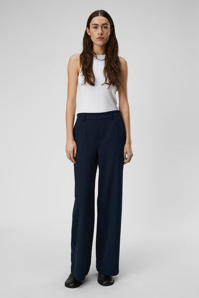 Pantalon bleu d'OBJECT, avec des jambes larges et porté avec une chemise blanche.