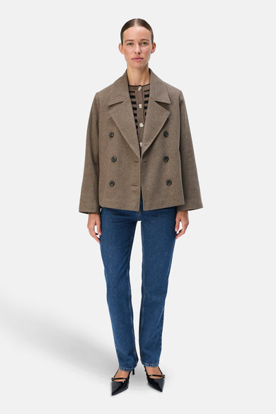 Bruine korte jas van OBJECT, met een dubbele knoopsluiting en gedragen over een gestreepte cardigan, met blauwe jeans en zwarte hakken.
