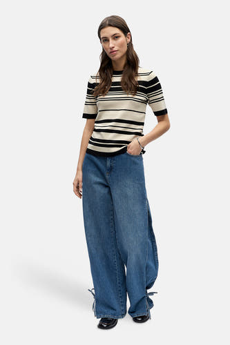 Pull multicolore à col rond de OBJECT, avec motif à rayures noires et jean ample avec fente et lacets en bas.