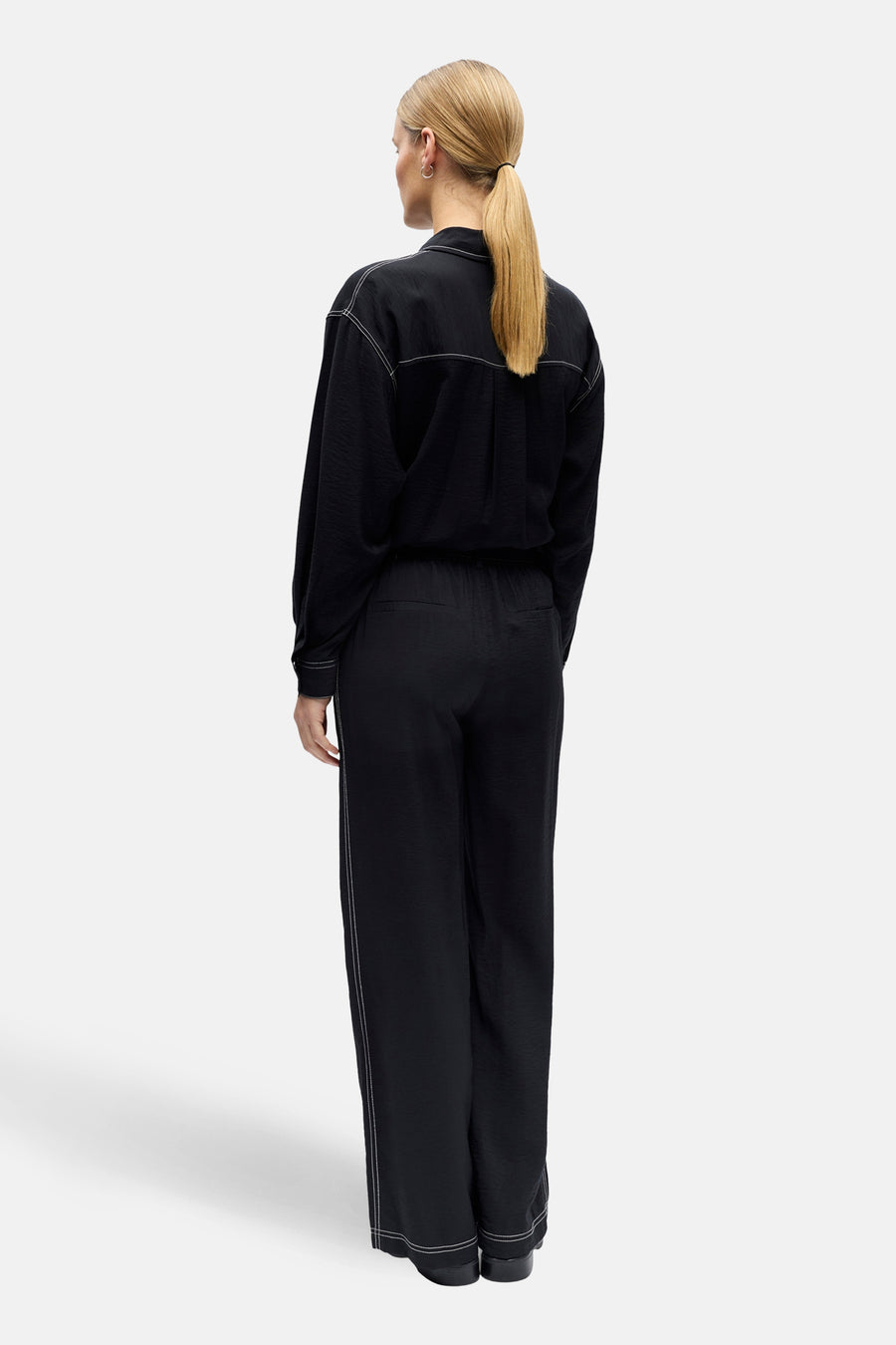 Pantalon noir OBJECT avec surpiqûres blanches, coupe décontractée et jambes larges, vu de dos.