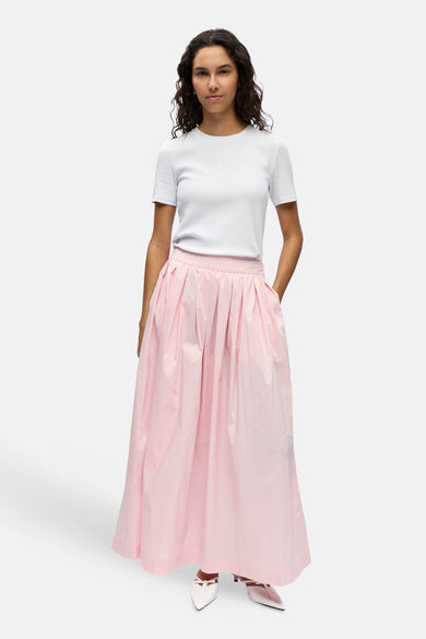 Lange roze geplooide rok van OBJECT met zakken, gedragen met een wit T-shirt en witte schoenen.