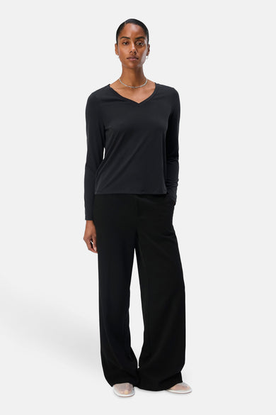 Zwart T-shirt met lange mouwen van OBJECT, met V-hals en gedragen met wijde, zwarte broek en open schoenen.

