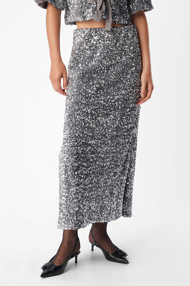 Lange zilveren rok van OBJECT, met pailletten en een split, gedragen met zwarte panty en schoenen.
