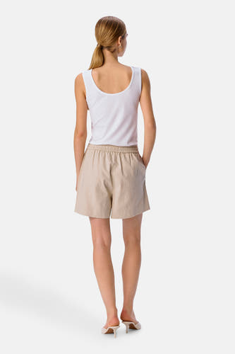 Ecru short van OBJECT, met elastische tailleband, gedragen met een wit hemdje en hakken.
