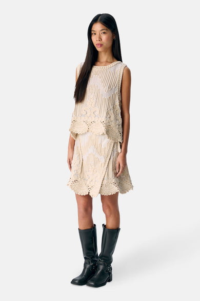 Ecru mouwloze blouse van OBJECT, met decoratieve opengewerkte details en gestyled met zwarte laarzen.
