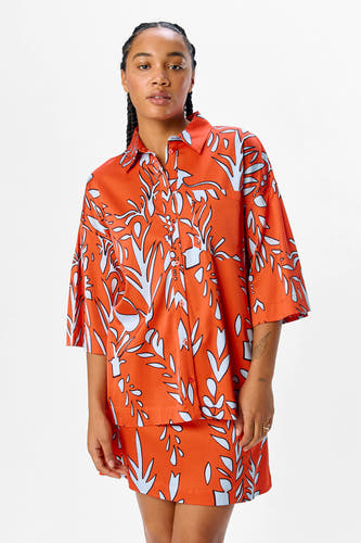 Oranje hemd met korte mouwen van OBJECT, met blauw bladmotief en bijpassende rok.
