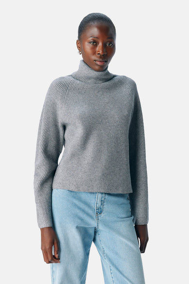 Grijze rolkraagtrui van OBJECT, met een ribgebreide textuur, gecombineerd met lichtblauwe jeans.
