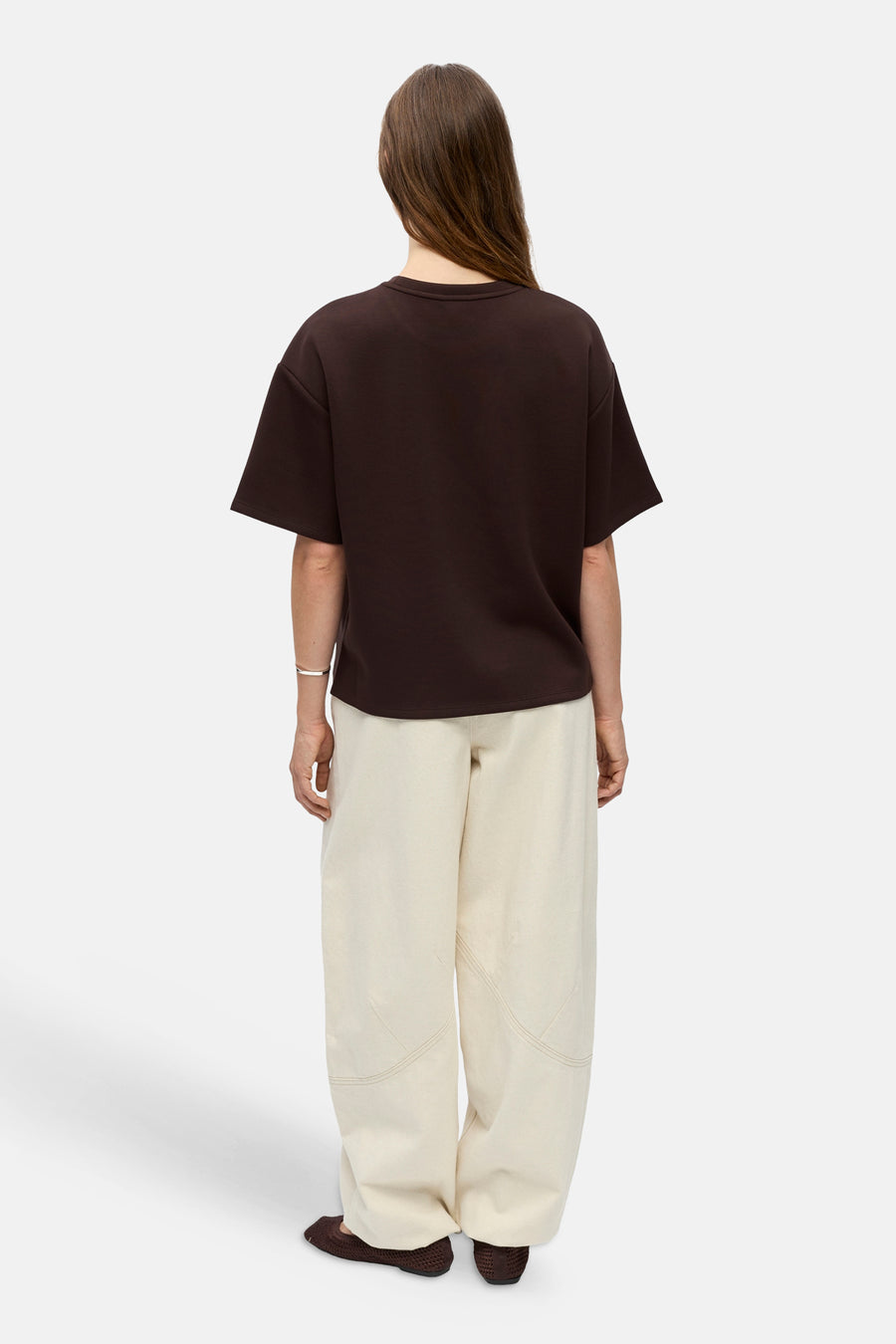 Bruine oversized sweater van OBJECT, achterkant weergegeven, met ronde hals en korte mouwen, gedragen met crèmekleurige broek en bruine slippers.
