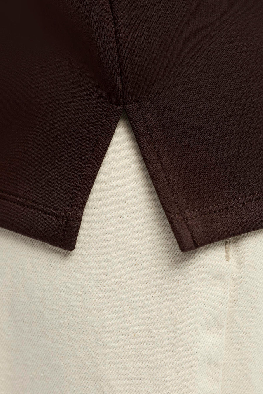 Bruine sweater van OBJECT, close-up van mouw met fijne naden en gladde stofstructuur op lichte achtergrond