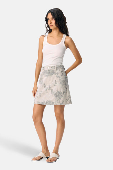 Korte ecru rok van OBJECT, met bloemen en vogelprint, gecombineerd met witte top en sandalen.
