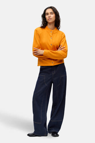 Oranje gilet van OBJECT, gedragen met een wijde donkere jeans en zwarte schoenen.
