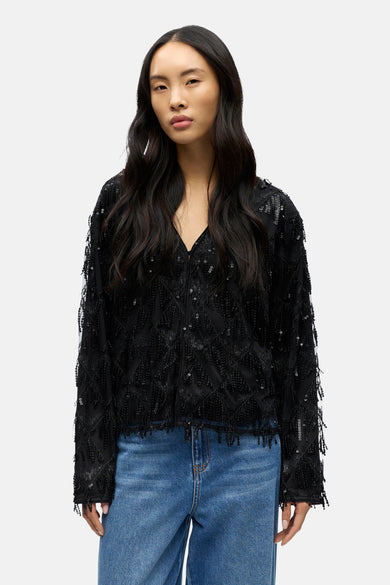 Zwarte blouse met lange mouwen van OBJECT, gedetailleerd met pailletten en gecombineerd met een blauwe jeans.
