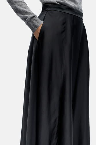Robe longue noire d'OBJECT, portée avec une main dans la poche, associée à un pull gris.