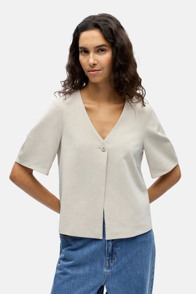 Ecru gilet van OBJECT, met V-hals en enkele knoopsluiting, gedragen met een blauwe jeans.
