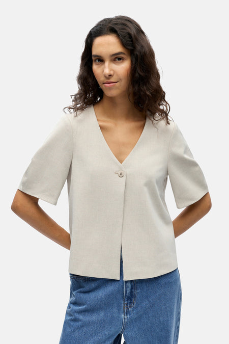 Ecru gilet van OBJECT, met V-hals en enkele knoopsluiting, gedragen met een blauwe jeans.
