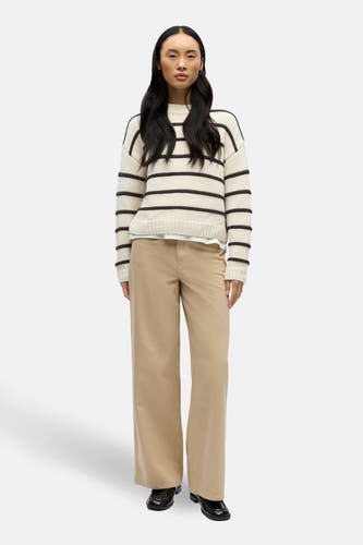 Gilet rond encolé écru d'OBJECT, avec des rayures brunes, porté avec un pantalon beige et des chaussures noires.