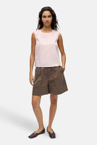 Roze mouwloze blouse van OBJECT, gedragen door een model met een bruine korte broek en donkerbruine platte schoenen.