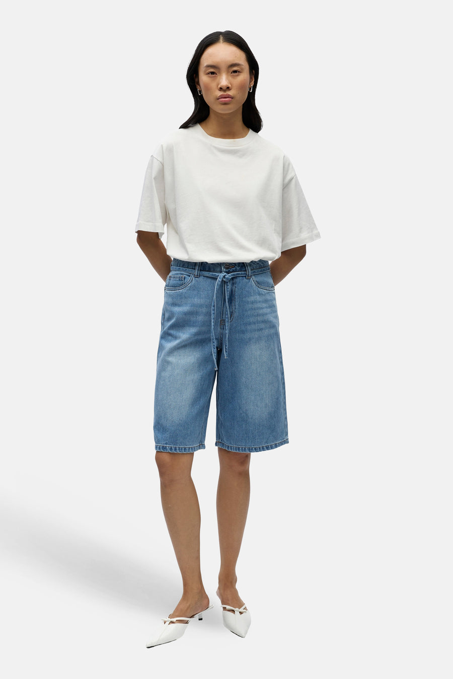 Korte lichtblauwe denim broek van OBJECT, met een hoge taille en een koord, gecombineerd met een wit T-shirt en witte muiltjes.
