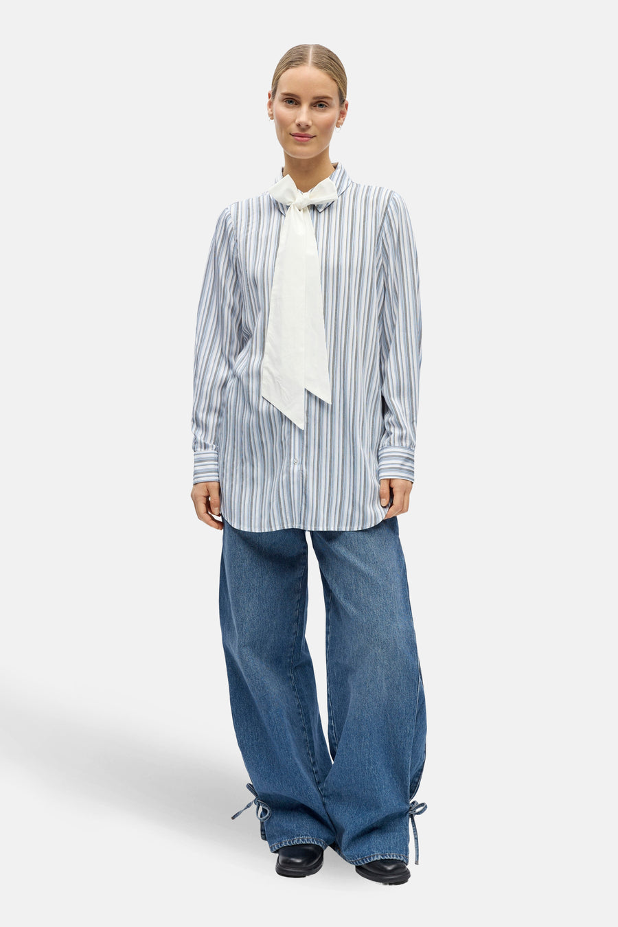 Blauw gestreept overhemd met lange mouwen van OBJECT, met witte strik en gecombineerd met wijde jeans.
