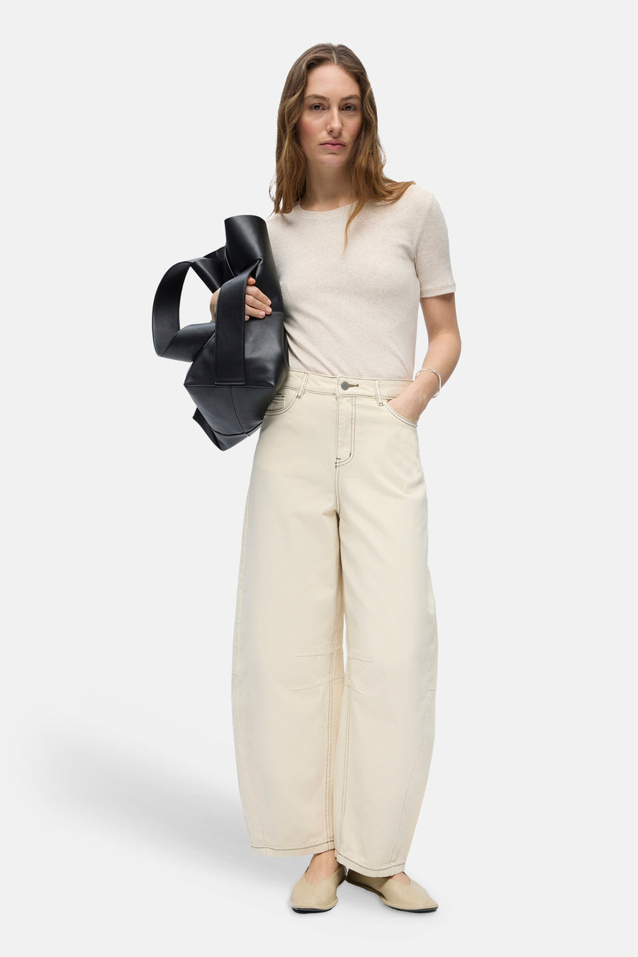 Beige jeans met speciale pasvorm van OBJECT, met wijde pijpen, contrasterende stiksels, gestyled met een crèmekleurig T-shirt, zwarte geknoopte tas en platte schoenen.