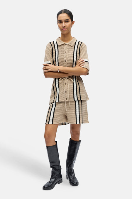 Beige gebreid hemd met korte mouwen van OBJECT, met verticale zwarte en witte strepen en kraag, gedragen met bijpassende shorts en laarzen.