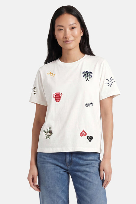 T-shirt multicolore d'OBJECT avec motifs colorés brodés, porté à l'envers, combiné avec un jean ample et des talons.