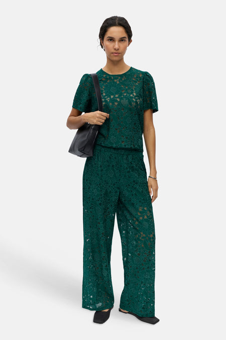 Pantalon vert de OBJECT avec motif de fleurs en dentelle, coupe ample, porté avec un haut assorti et des mules noires.