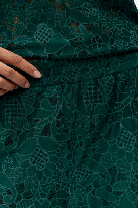 Pantalon vert de OBJECT avec un motif délicat de fleurs et de feuilles en dentelle et une main à la ceinture.